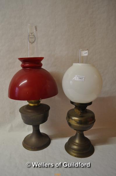 Two brass or copper oil lamps, one with milk glass shade, the other red glass.