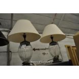 A pair of glass ovoid table lamps with cream shades, 51cm overall.