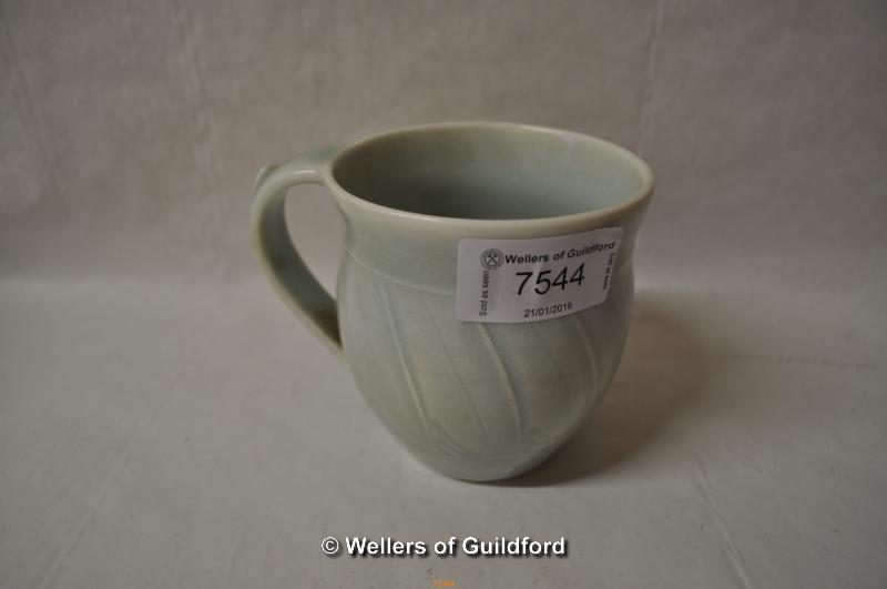 A small pottery mug in pale green glaze, with stylised wrythen pattern, impressed star mark at