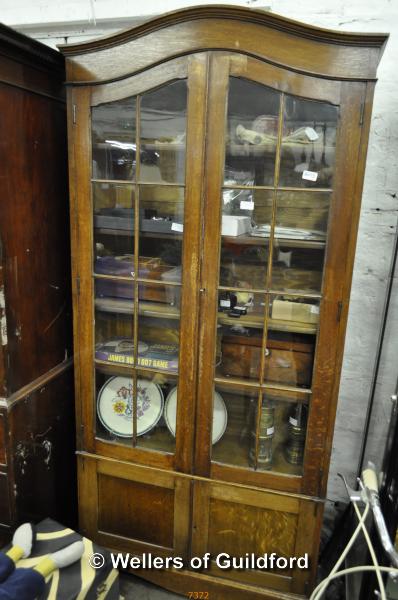 An early C20th oak display cabinet with arched top, two glazed doors enclosing shelves, 196 x 92.