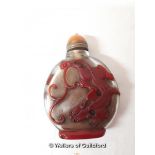 A Chinese glass snuff bottle decorated with red dragons.