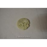 A pale green jade pendant carved with a dragon and figure, 5.5cm diameter.