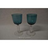 Two green glass drinking glasses with clear stems, the tallest 13.75cm.