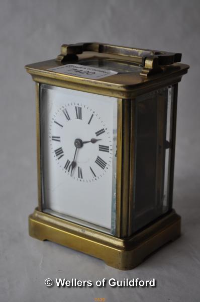 A brass carriage clock , the white enamel dial with Roman numerals, 10.75cm excluding handle.