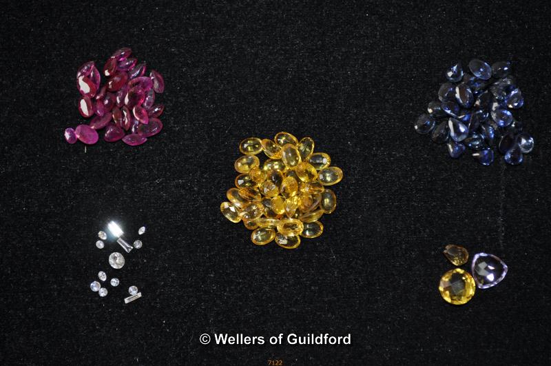 Quantity of loose gemstones including diamonds, sapphires, rubies, and yellow topaz/citrine.