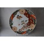 A Japanese porcelain plate decorated with a figure, prunus and parasols, 31cm.