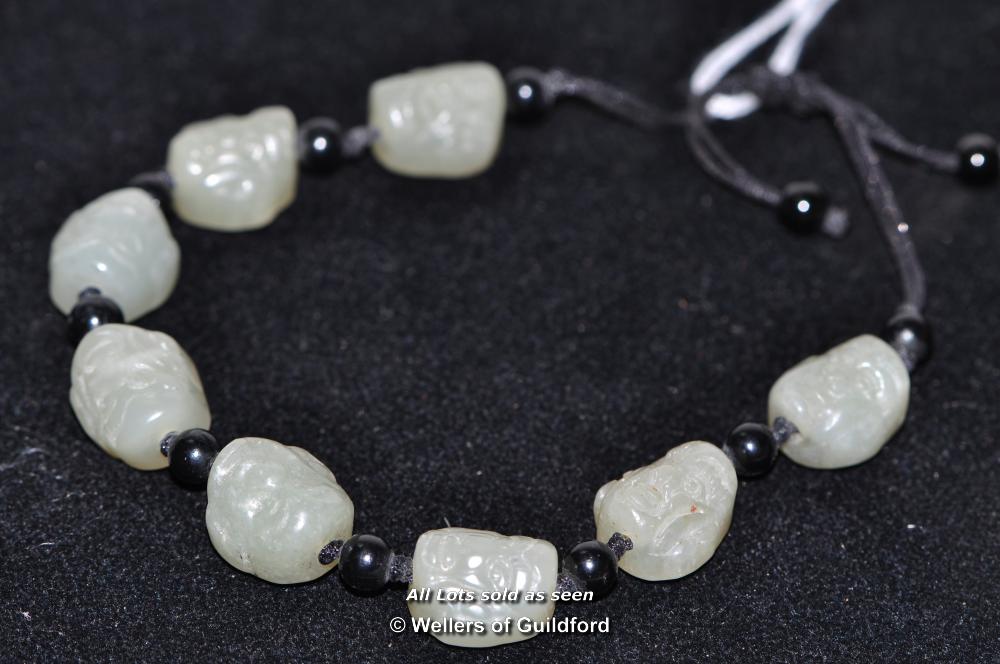 A Chinese bracelet formed of eight hardstone beads carved with immortals' heads.