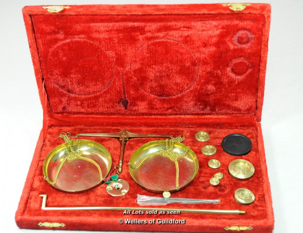 A set of balance scales and weights, to weigh up to 100g in red fabric case.