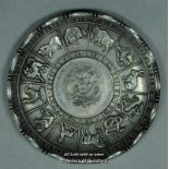 A Chinese white metal dish embossed with signs of the zodiac, coin inset to centre, stamped