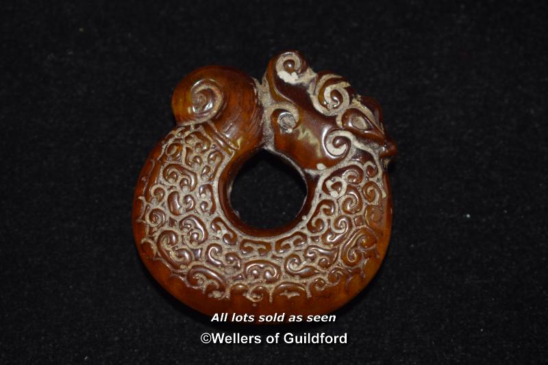 A Chinese amber pendant carved as a dragon.