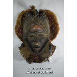 An African carved wooden mask decorated with cowrie shells and horns, 50cm.