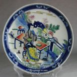 A Chinese plate painted with figures at a table, two rings to base, 22cm diameter.