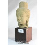 A Cambodian carved stone head, mounted on a wooden stand, 26.5cm overall.