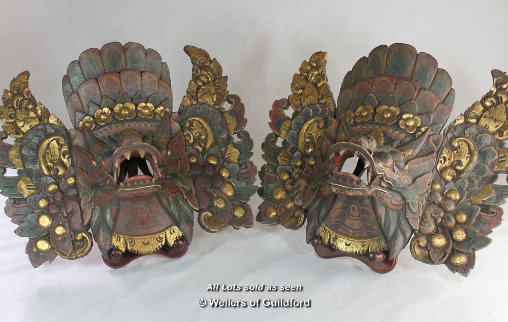 A pair of Balinese masks carved and gilded as mythical beasts.