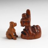 2 Netsuke.Sitzender Hund aus Buchsbaum, signiert, mit eingelegten Glasaugen. H 4 cm. /Okame