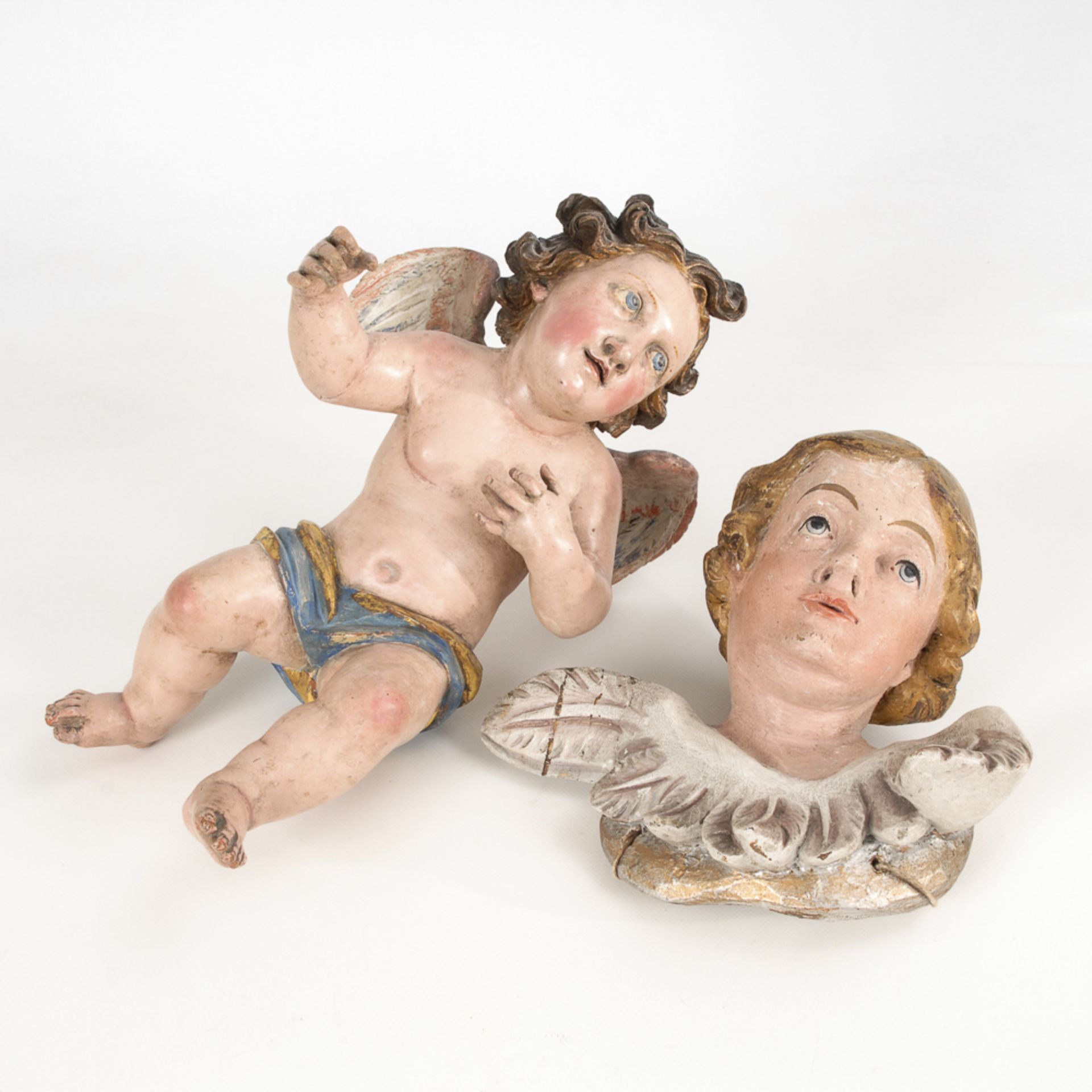 Barocker Engel und Engelskopf.18. Jh. Holz polychrom gefasst. H 39 bzw. 25 cm. Geflügelter Putto und