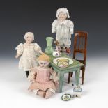 3 kleine Puppen, Tisch, Stuhl und Zubehör.Ca. 1900-30. Holz, Porzellan, Glas und Blech. H 5-23,5 cm.