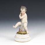 Putto mit Fisch, FÜRSTENBERG.F-Marke, 19. Jahrhundert. Farb- und goldstaffiert. H 14 cm. Auf einem