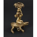 Figürlicher Bronzeleuchter.Anfang 20. Jh. H 21 cm. Auf einer Echse reitender, geflügelter Putto, der