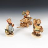 3 HUMMEL-Figuren: Kinderpaar mit Korb, Mädchen mit vollem Korb und Schirm,Junge auf Holzwagen.