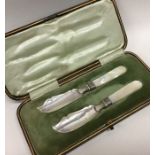 A pair of silver MOP butter spades contained withi