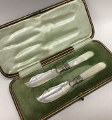 A pair of silver MOP butter spades contained withi