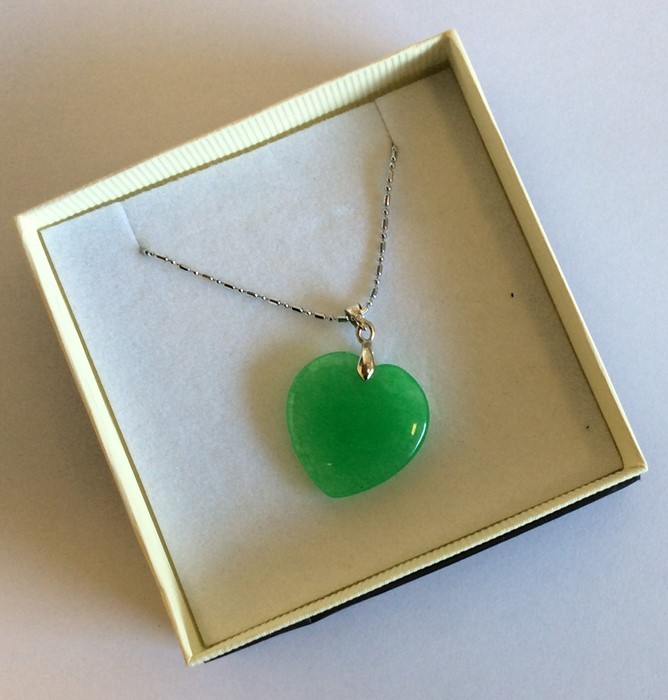 A small jade heart shaped pendant on fine link cha