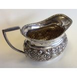 A small silver embossed cream jug with gadroon rim