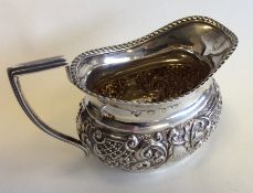 A small silver embossed cream jug with gadroon rim