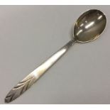 A stylish silver preserve spoon decorated with a w