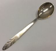A stylish silver preserve spoon decorated with a w