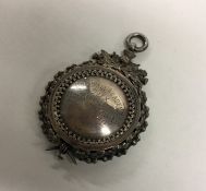 A circular silver fob attractively decorated with