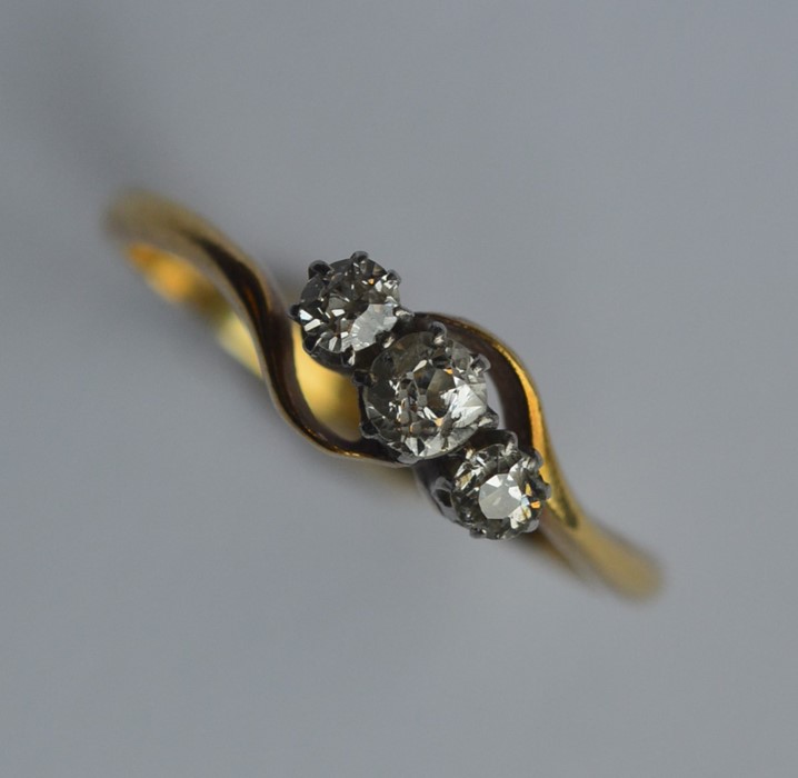 A diamond three stone crossover ring in 18 carat m