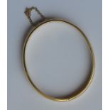 A gold hinged bangle with safety chain. Approx. 12