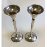 A pair of tapering circular silver candlesticks. A