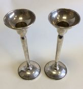A pair of tapering circular silver candlesticks. A