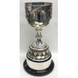 A massive silver embossed trophy cup on pedestal b