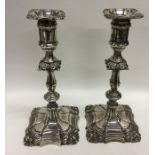 A pair of silver candlesticks embossed with scroll