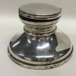 A large capstone silver inkwell on circular base.