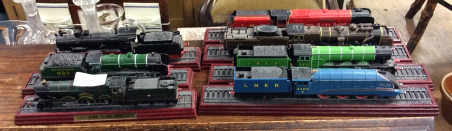 Seven 00 gauge model trains on stands.