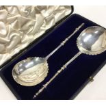 A boxed pair of Edwardian silver preserve spoons.