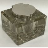 A heavy glass and silver mounted hinged top inkwel