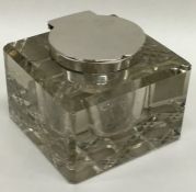 A heavy glass and silver mounted hinged top inkwel