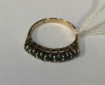 An emerald and diamond half hoop ring in gold. Est