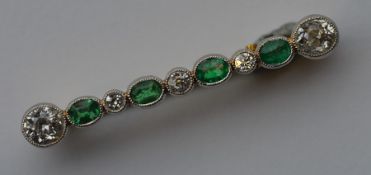 An attractive emerald and diamond nine stone brooc