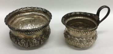 A pair of Edwardian embossed silver cream and suga