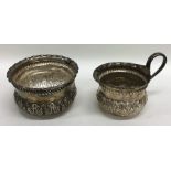 A pair of Edwardian embossed silver cream and suga