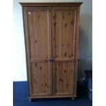 A large pine two door wardrobe on bun feet. Est. £