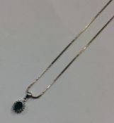 An emerald and diamond drop pendant on fine link c