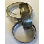 A silver hinged bangle together with two others. A